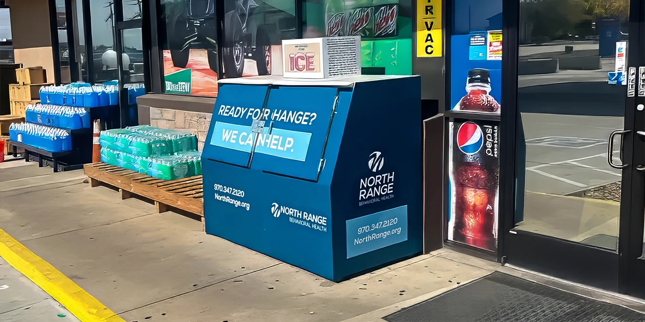 Convenience store entrance with blue bin, water bottles, and Pepsi advertisement. Transcribed Text: READY FOR CHANGE? WE CAN HELP. NORTH RANGE BEHAVIORAL HEALTH 970.347.2120 NorthRange.org