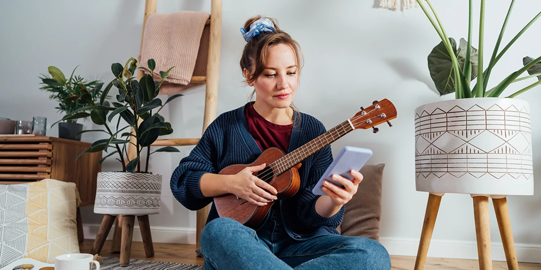 Woman looking at her phone learning how to play the ukulele